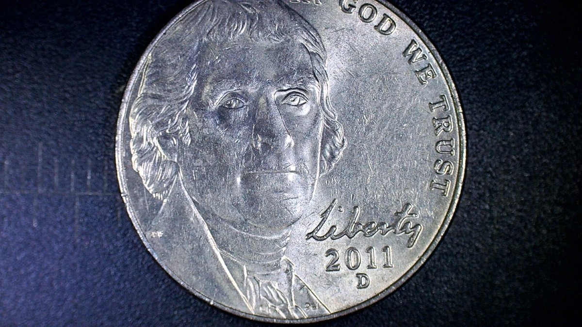 2011 Jefferson nickel die cud error showing a raised blob of metal at the rim with a corresponding flat weakness in the adjacent design
